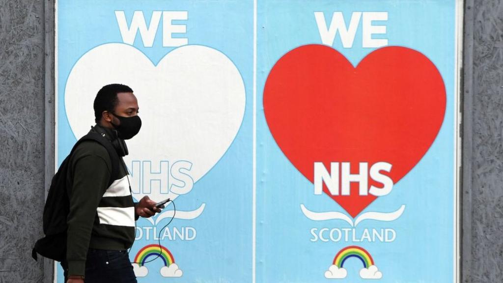 Man walking past NHS sign in Glasgow