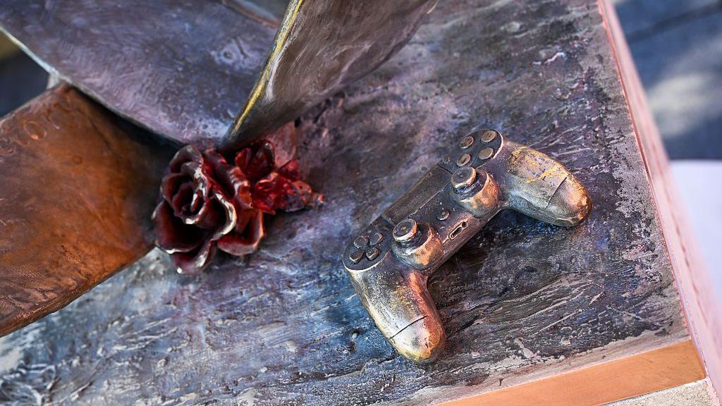 Una flor y un mando de PlayStation en el monumento en honor a Diogo Jota y Andre Silva.