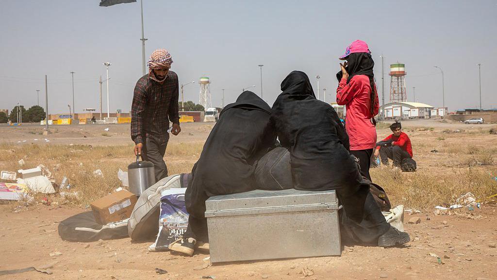 Afghan deportees sit near the border at Islam Qala crossing on July 4, 2025. Mass expulsions surged after the IranIsrael war, with Iranian authorities accusing Afghans of espionage and deporting thousands daily.