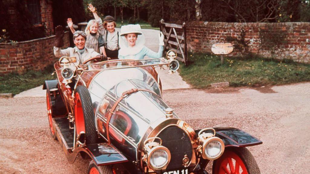 Dick Van Dyke, Heather Ripley, Adrian Hall and Sally Ann Howes sit waving from their seats in the car, in a publicity portrait issued for the film , Chitty Chitty Bang Bang'