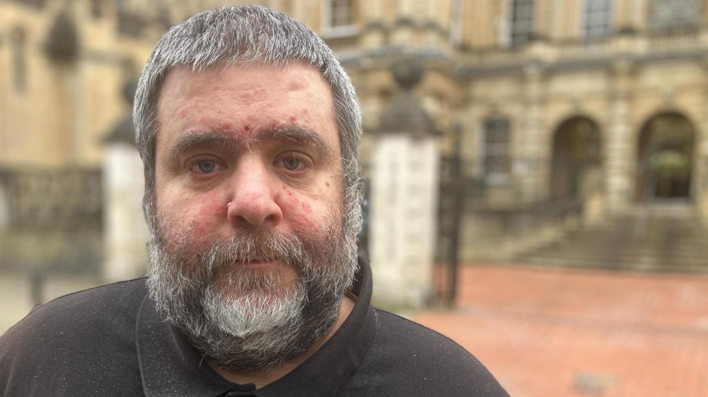 Barry O'Sullivan, who has grey, short hair and a grey, short beard, stood in front of Reading Crown Court. He is wearing a black T-shirt.