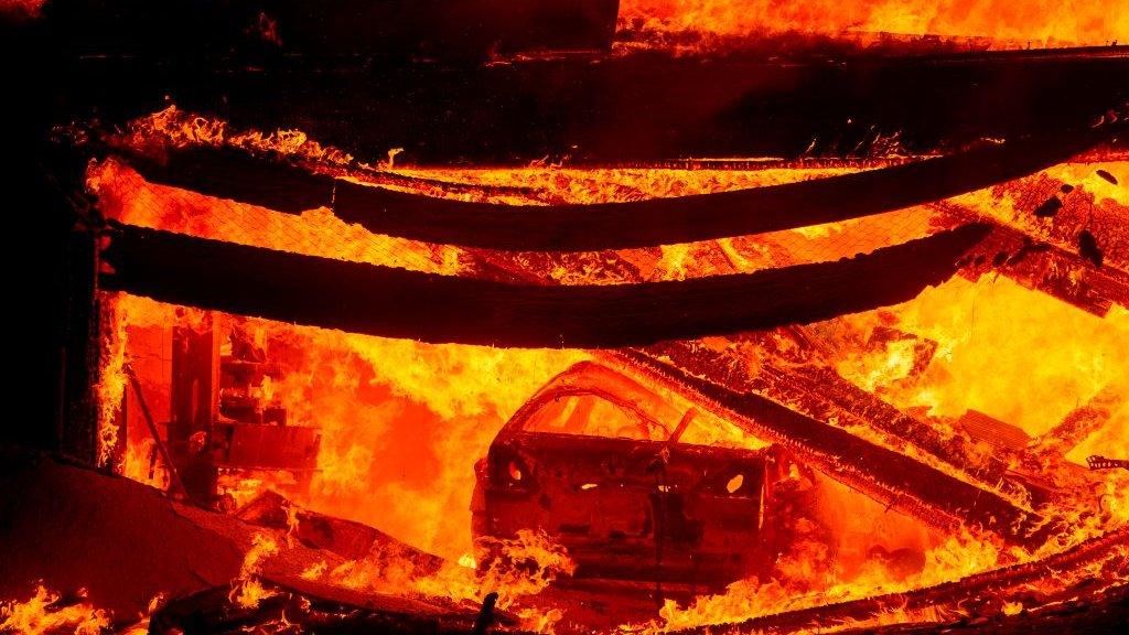 A car burns in a garage during the Hillside fire in the North Park, San Bernardino, California