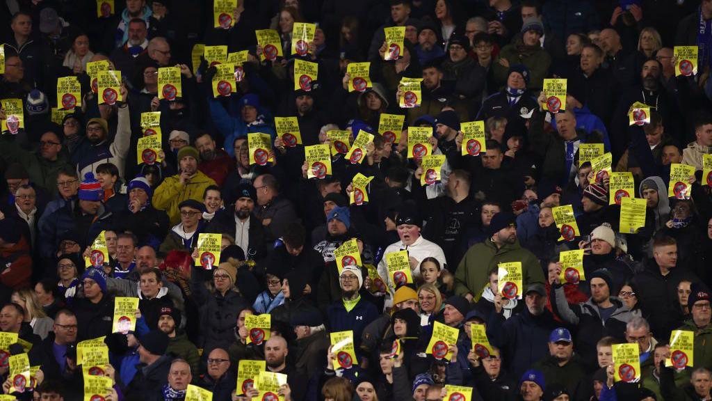 Sheffield Wednesday fans hold up yellow banners bearing slogans protesting against Dejphon Chansiri's ownership of the club
