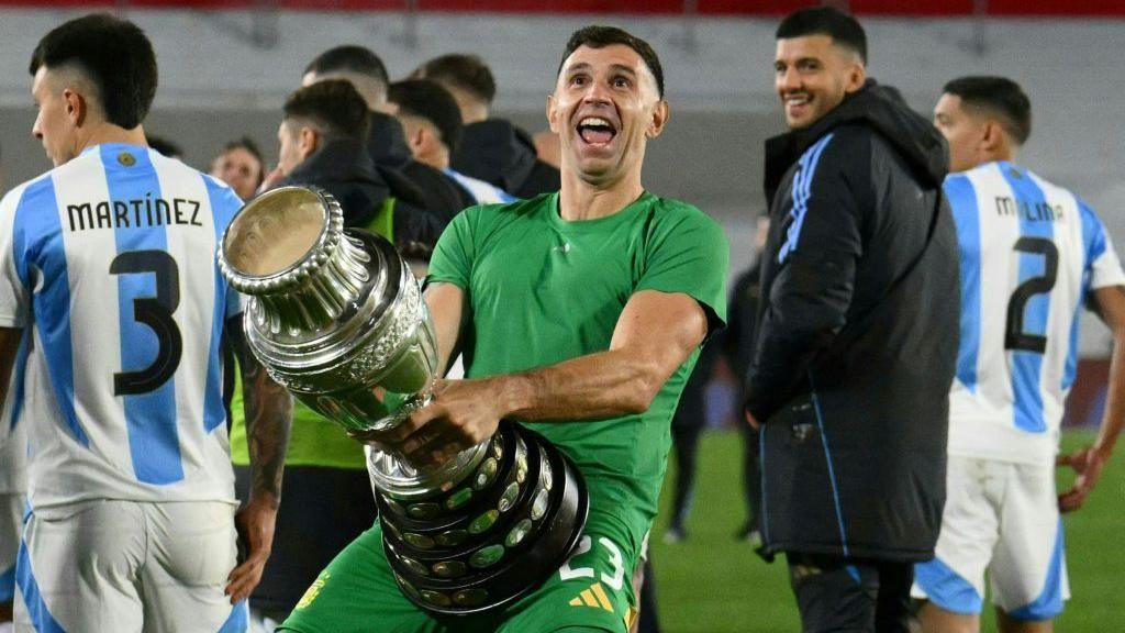 Argentina goalkeeper Emiliano Martinez holds a replica Copa America trophy against his crotch