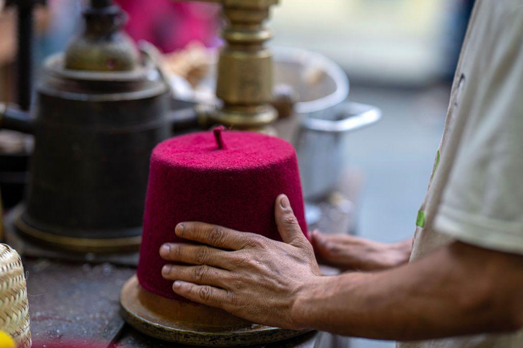 A man shapes felt over a mould to make a fez - also known as a tarboosh.