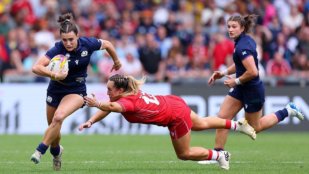 Francesca McGhie of Scotland breaks away with the ball as she evades a tackle from Courtney Keight of Wales