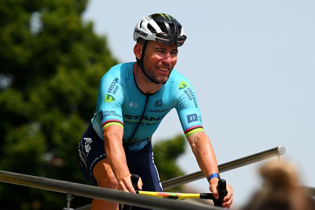 A man cycling wearing a teal blue cycling top and helmet.