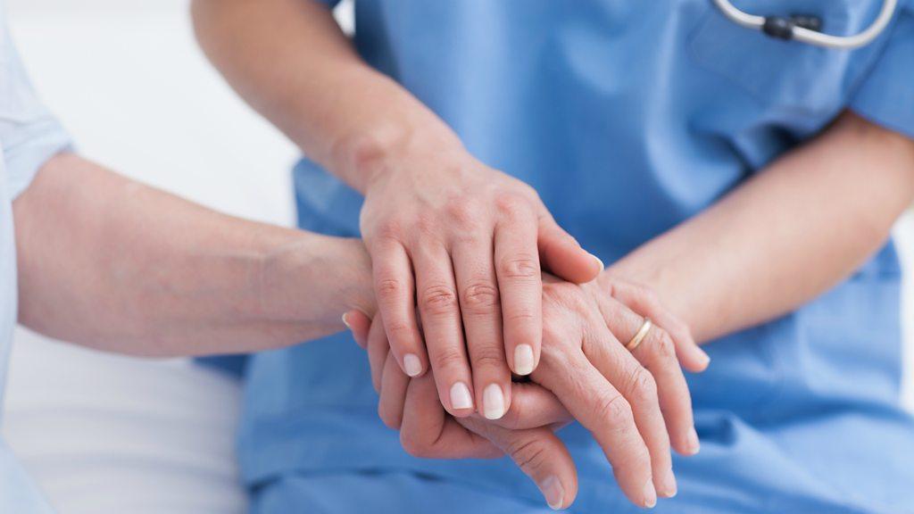 A nurse holding the hand of a patient