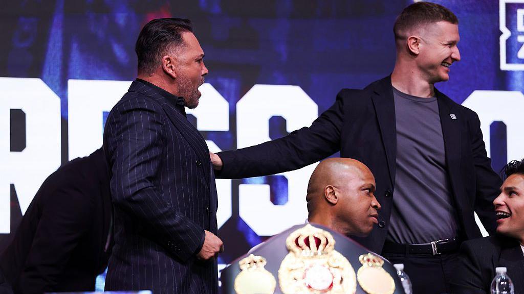 Oscar De La Hoya is stopped from moving across the stage at a news conference