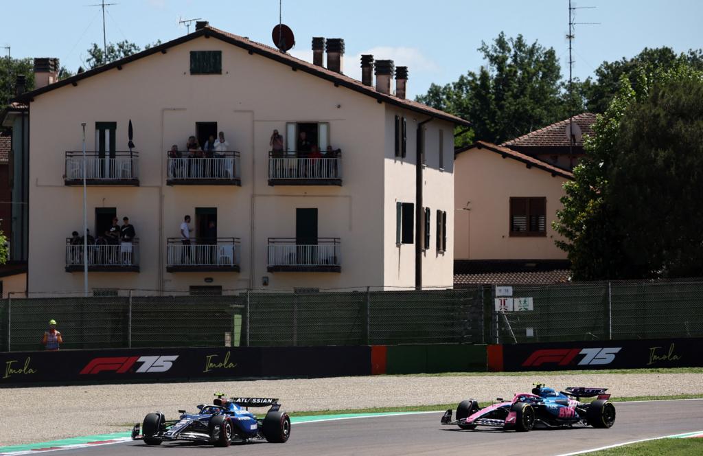 The Williams of Carlos Sainz leads the Alpine of Franco Colapinto with a house in the background in Imola