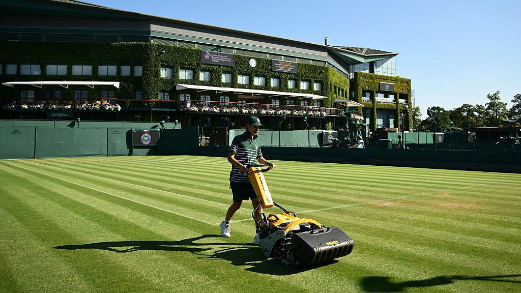 A groundskeeper mowing a court a Wimbledon