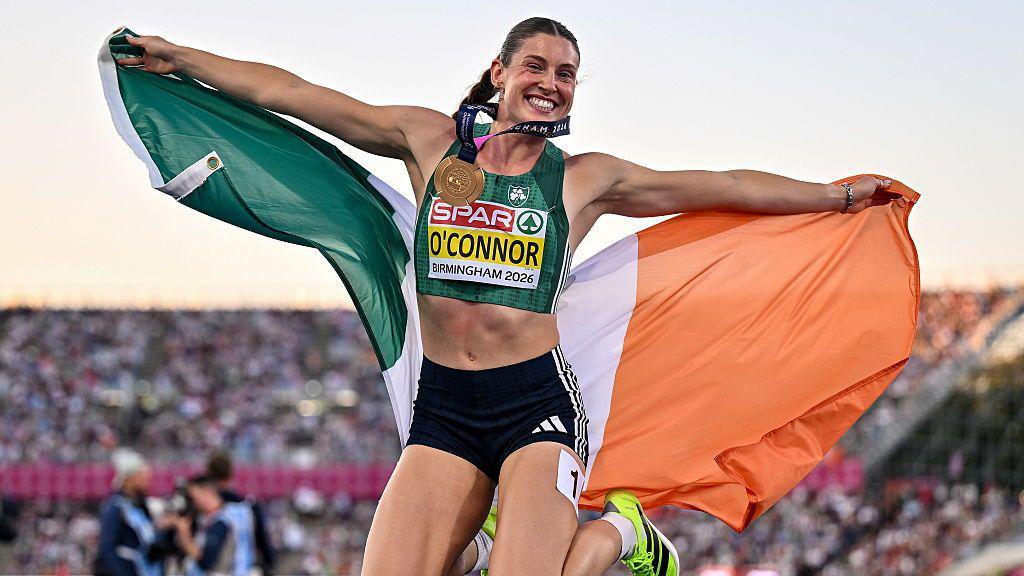 Kate O'Connor holds the Irish flag and jumps in celebration with her gold medal after winning the women's heptathlon during day six of the European Athletics Championships