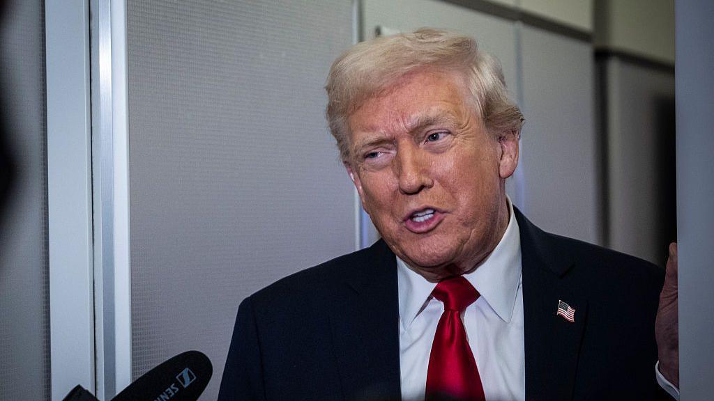 Trump midspeech. it is a close up of him. He is wearing a suit, white shirt and red tie