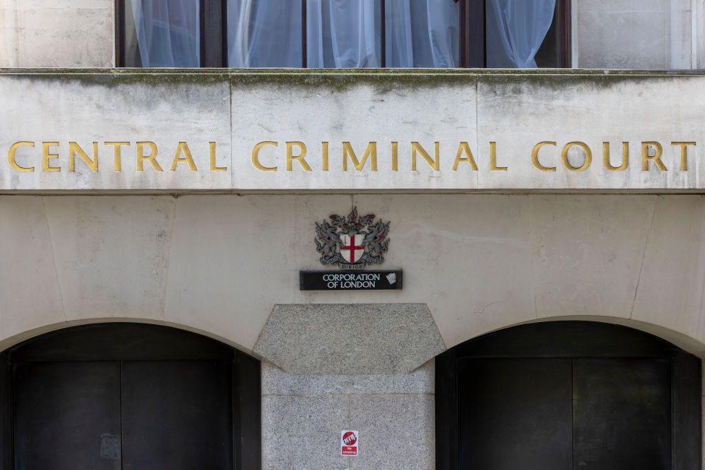 Library shot of the outside of the Old Bailey. It shows the entrance door with "Central Criminal Court" engraved in gold into the marble wall above. Below is a small sign saying Corporation of London, and beneath that is a small sticker to inform passers-by there are CCTV cameras.