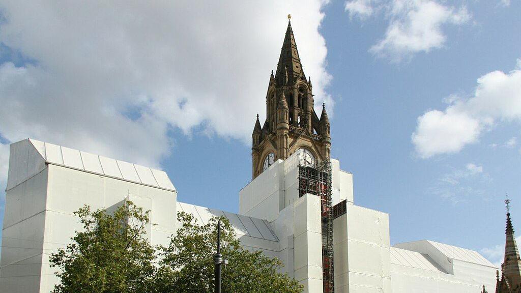 The pointed neo-Gothic top of the town hall peeks above a massive white wrap-around that rises above surrounding trees