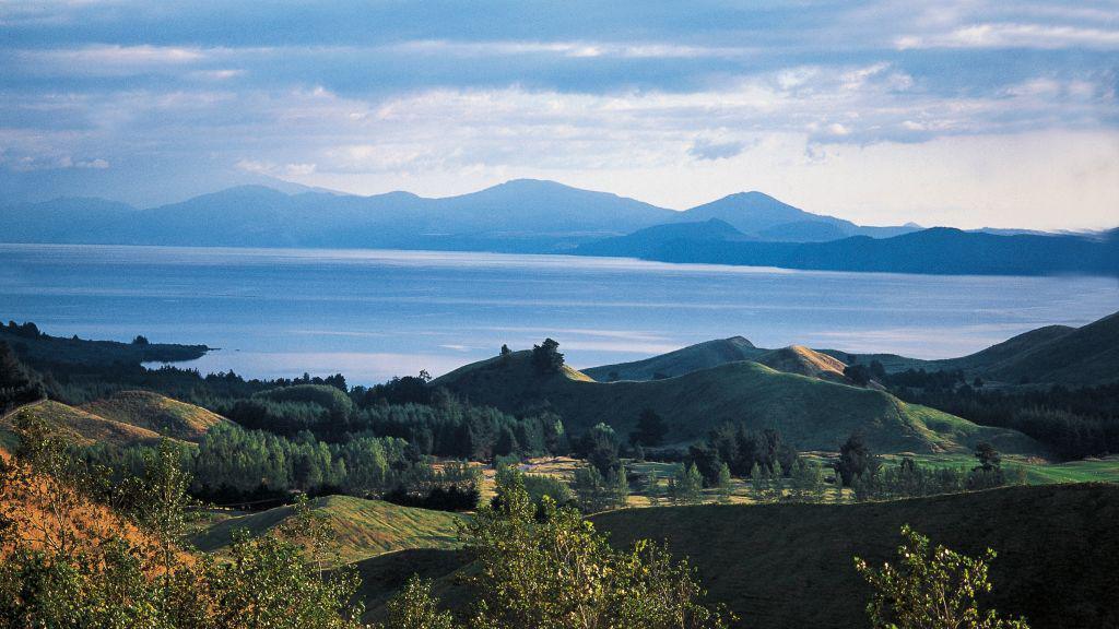 Lake Taupō is seen from a distance. Mountains are in the background.