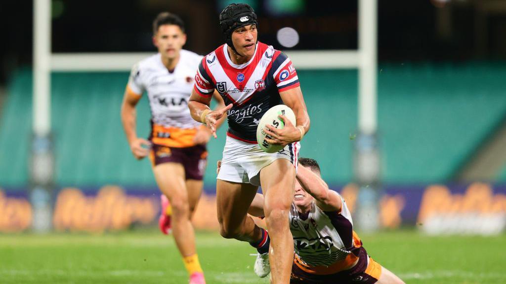 Joseph Suaalii pictured on debut for Sydney Roosters in May 2021, accelerating away from a Brisbane Broncos players who tries to tackle him