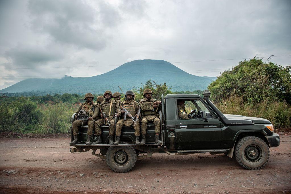 A Congolese army pick up truck carrying troops during clashes between the Congolese army and M23 rebels. A mountain can be seen in the background as the truck carrying the troops drives by. 