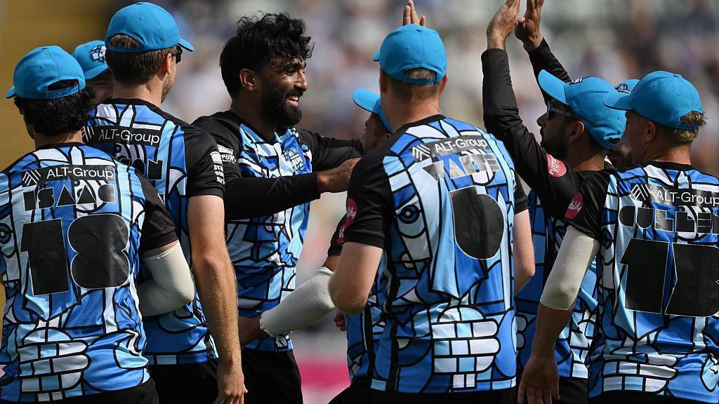 Worcestershire Rapids players in patterned kit of various shades of blues celebrate a wicket