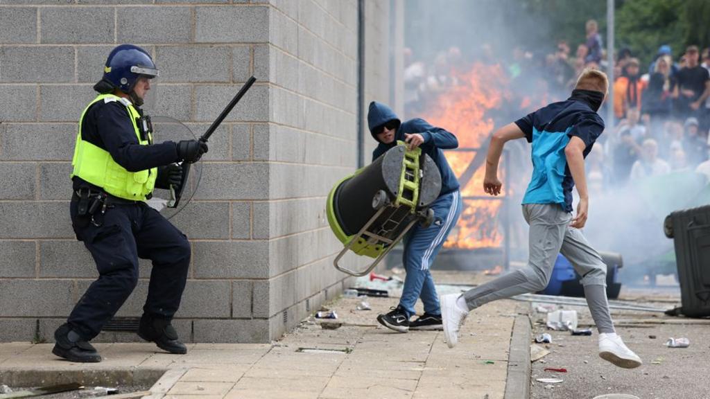 Οι διαδηλωτές αντιμετωπίζουν αστυνομικούς έξω από ξενοδοχείο κατά τη διάρκεια διαμαρτυρίας στο Ρόδεραμ την Κυριακή