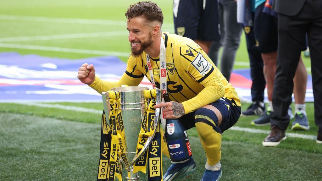 Joe Bennett of Oxford United poses with the League One play-off final trophy