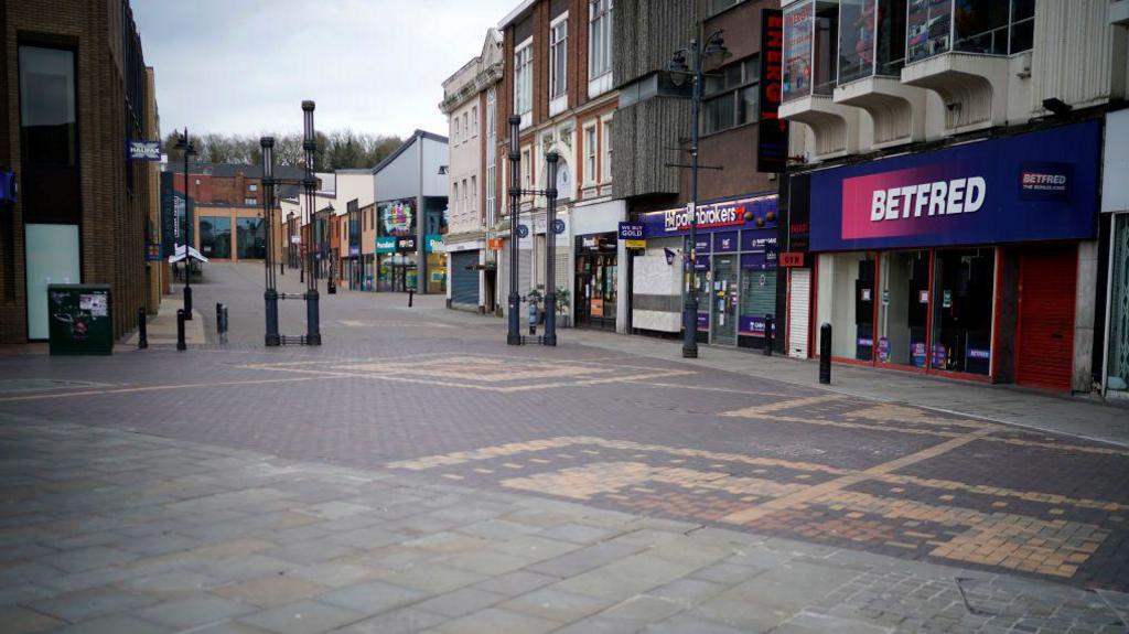 Walsall town centre. There is nobody on the street. There is a Bet Fred and a pawnbrokers. 