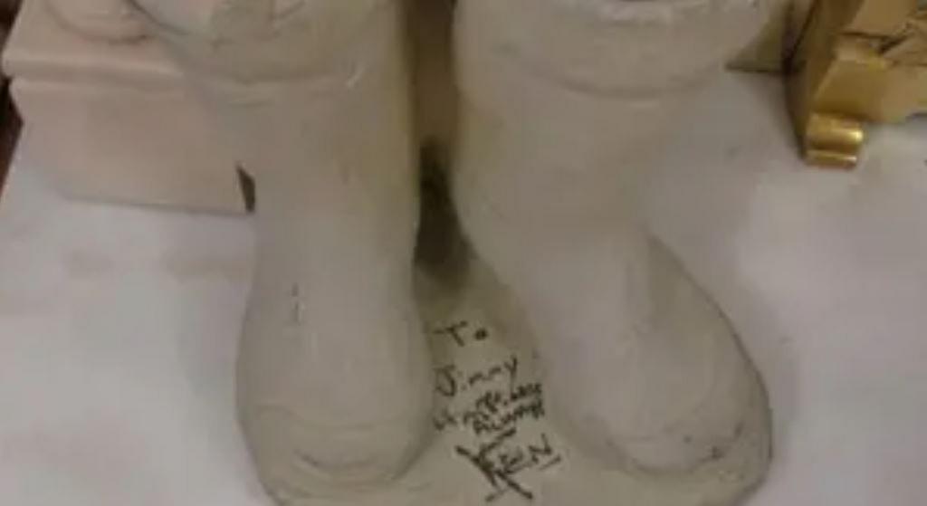 A concrete statue of a pair of Wellington boots, signed by Ken Dodd in black ink