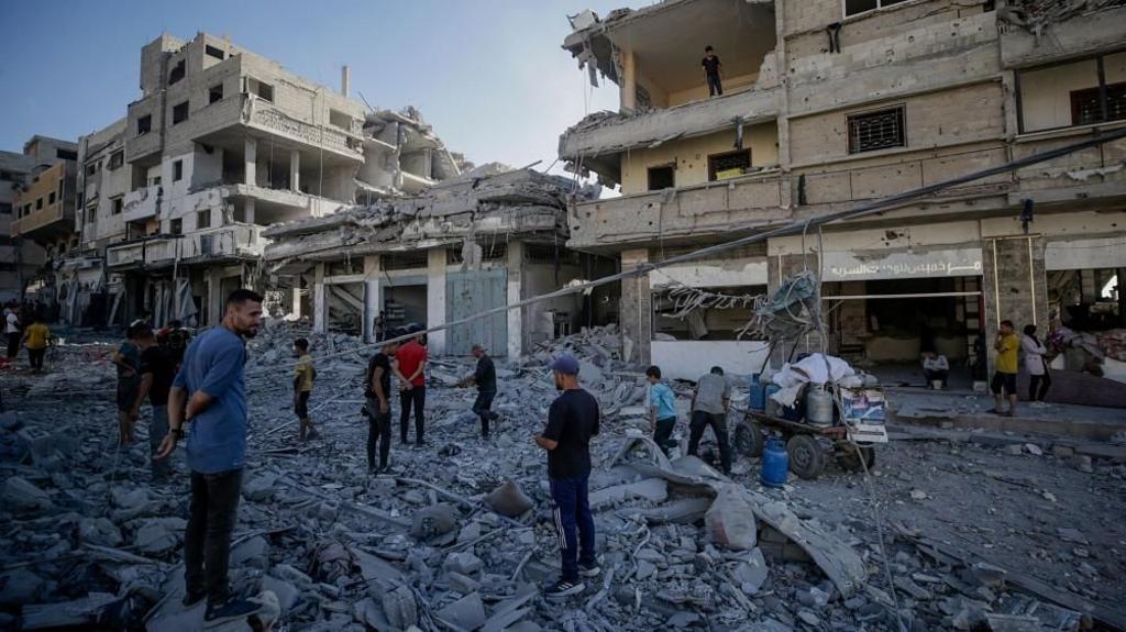 A group of Palestinians stand on the rubble of a building. 