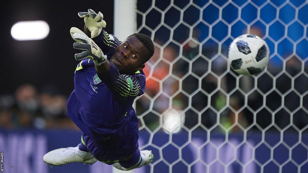 Francis Uzoho hangs almost horizontally in the air as he dives in vain to save a ball that is passing him into the net