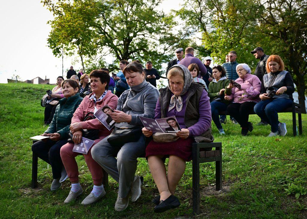 Elderly women sat on a park bench listen to a speech of independent Moldovan presidential candidate Victoria Furtuna during a campaign event 