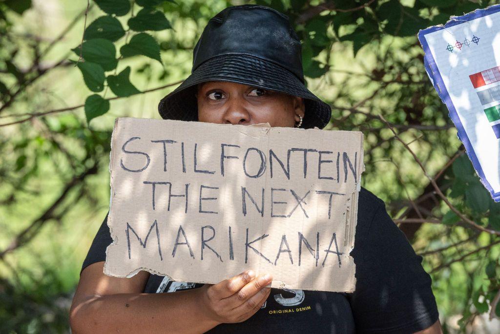 A woman pickets the mine in Stilfontein with a sign that reads: '"Stilfontein is the next Marikana".