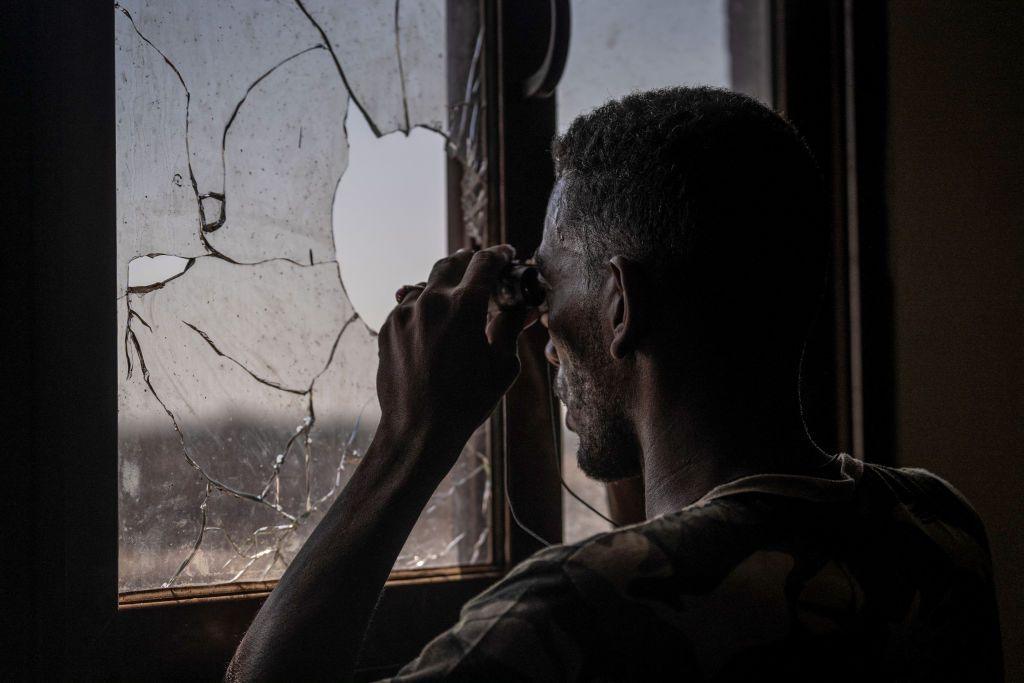 A bearded army soldier, viewed from behind, scans the frontline with binoculars through a broken window in Khartoum, Sudan - Sunday 3 November 2024