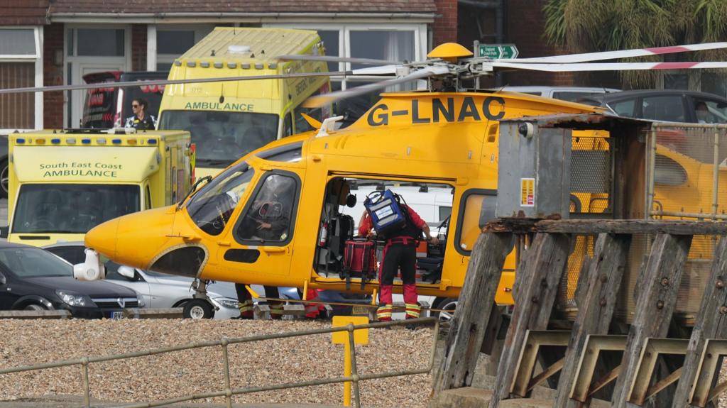 Numerous ambulances and a coastguard helicopter at the scene on the water's edge