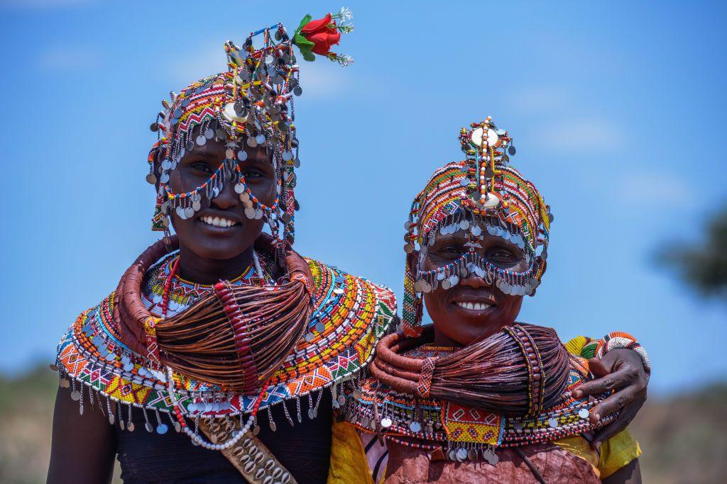 Two women from the Rendille community stand side-by-side, wearing brightly beaded jewellery and headdresses. 