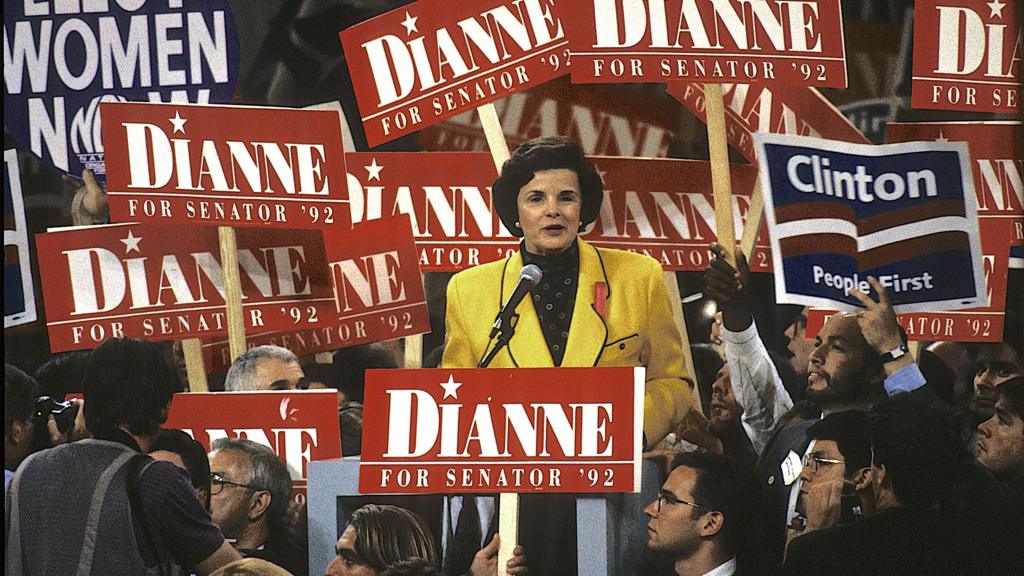 Dianne Feinstein, then Mayor of San Francisco, addresses the Democratic National Convention in 1992, ahead of being elected to the Senate. She's wearing a yellow suit with red 'Dianne' banners all around her