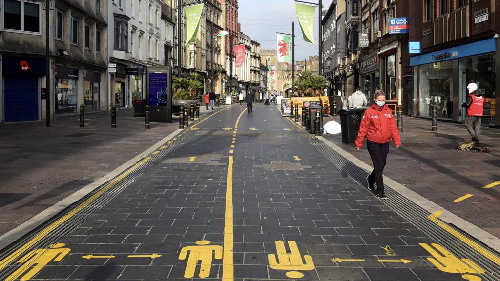 A person wears a facemask as they walk through Cardiff city centre, during the Covid-19 pandemic.