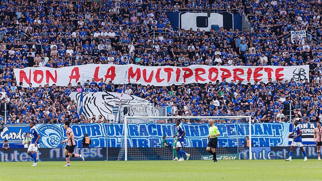 Strasbourg's ultras hold up a banner in protest at the club being part of a multi-club ownership structure