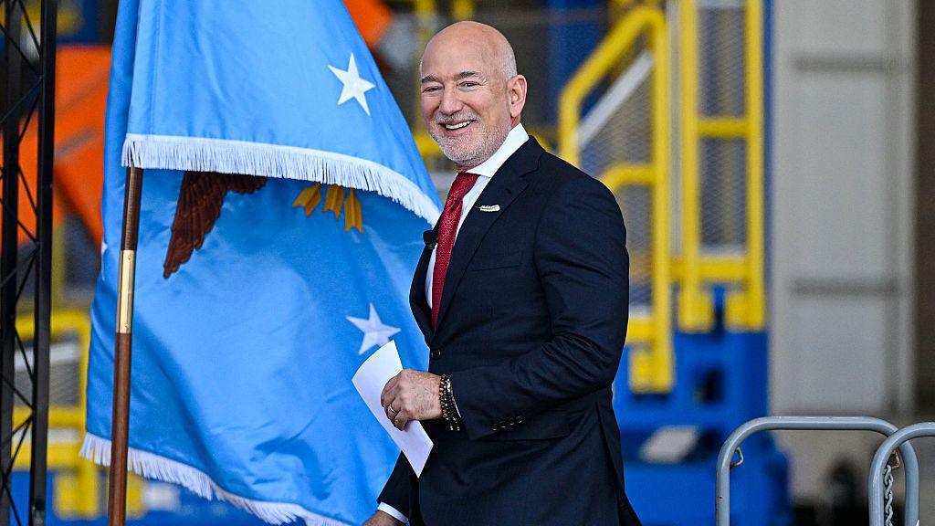 Blue Origin boss Jeff Bezos smiling and walking holding a piece of paper, in an image taken in February 