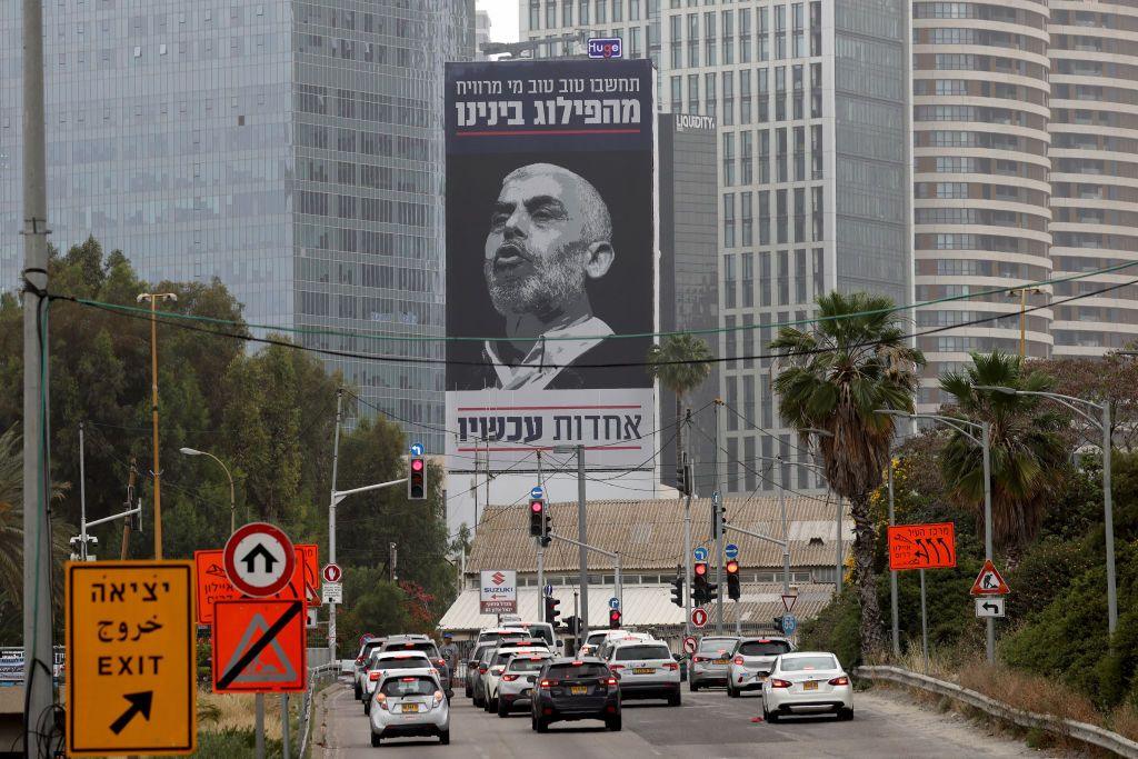 Cars in Tel Aviv drive past a poster of Sinwar, with a message in Hebrew urging Israelis to unite against their most wanted enemy