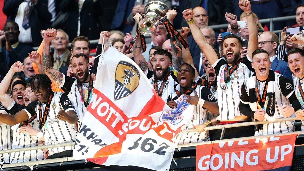 Notts County hold the trophy aloft on the balcony at Wembley after winning the National League promotion final