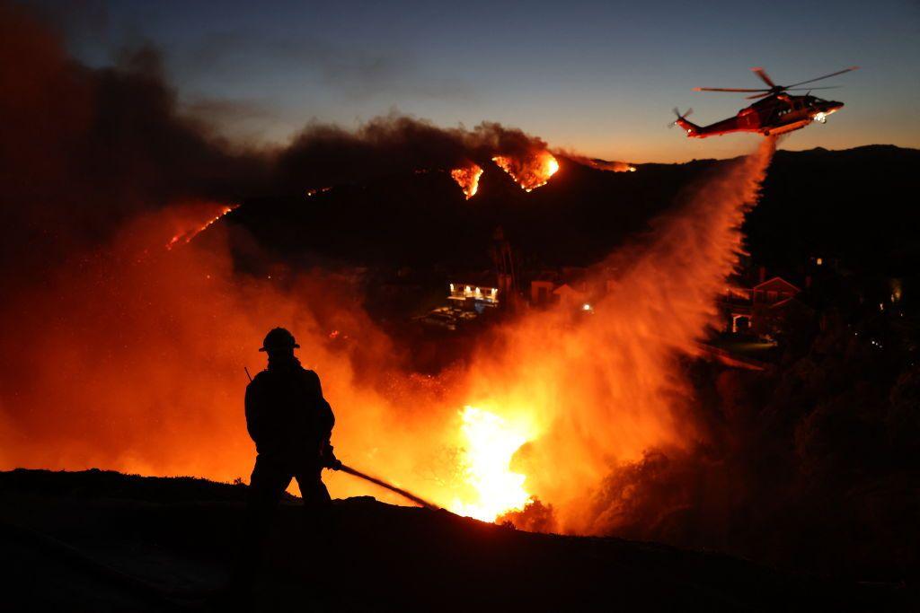 A firefighter and helicopter tackle fires in Los Angeles.