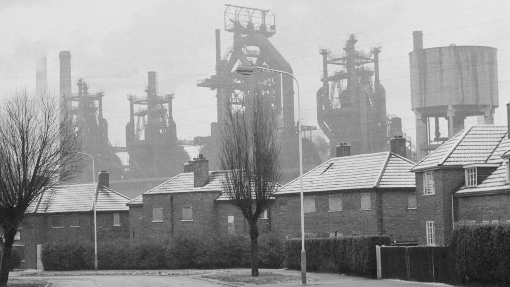 The steelworks in Corby against the skyline, with a housing estate in the foreground