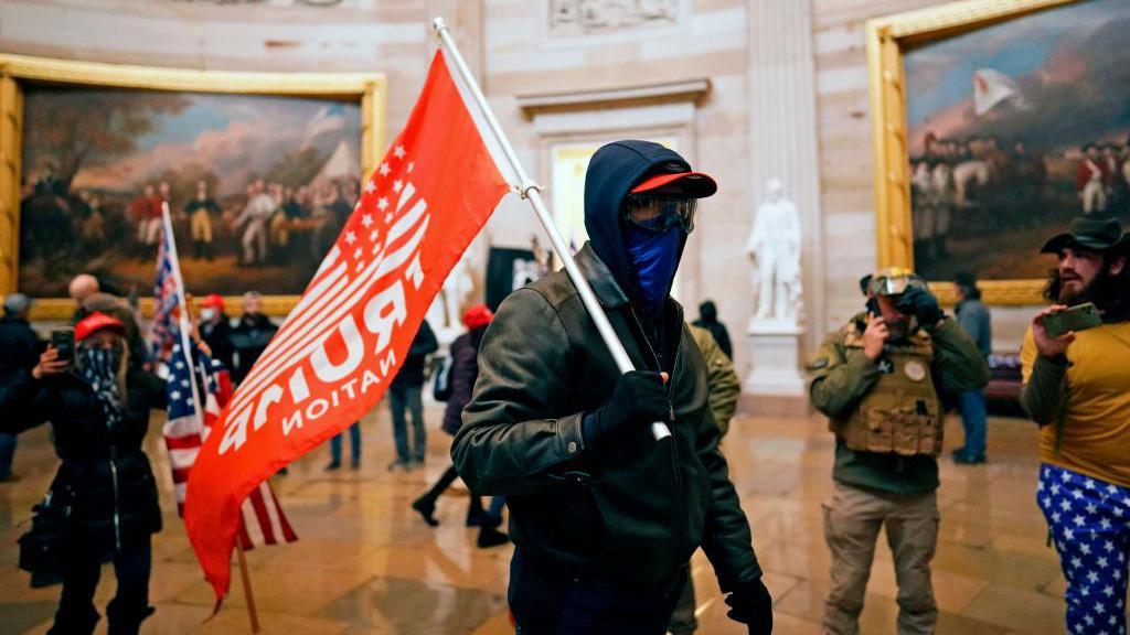 A man holds a trump flag in the capitol