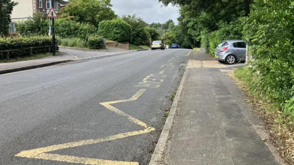 Faded crossing road markings on a road in Caterham outside Clifton Hill School 