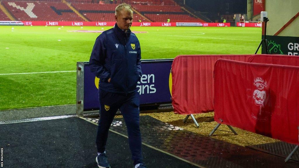 Oxford United's former head coach Liam Manning leaves the pitch after a League One match leading the U's.