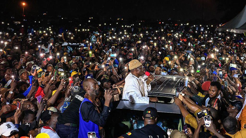 Supporters gather around Cameroonian presidential candidate Issa Tchiroma Bakary (C) during a campaign rally in Douala on 5 October 2025