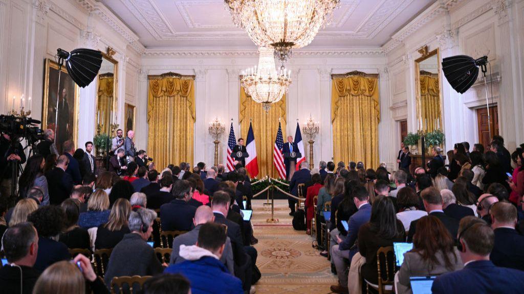 Members of the press sit in rows of seats as French President Emmanuel Macron and US President Donald Trump hold a news conference in the White House