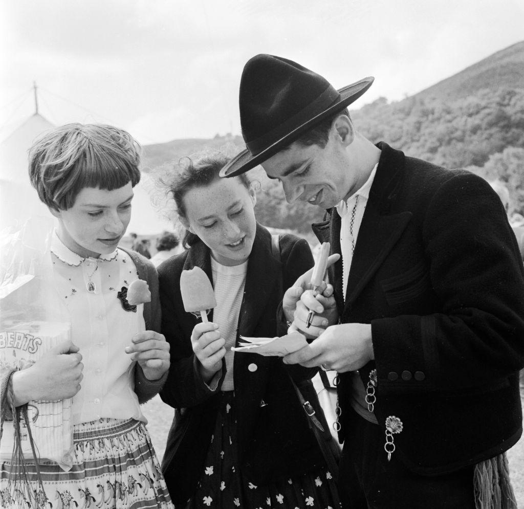 Dyn o bortiwgal mewn gwisg draddodiadol yn arwyddo llyfr lloffion