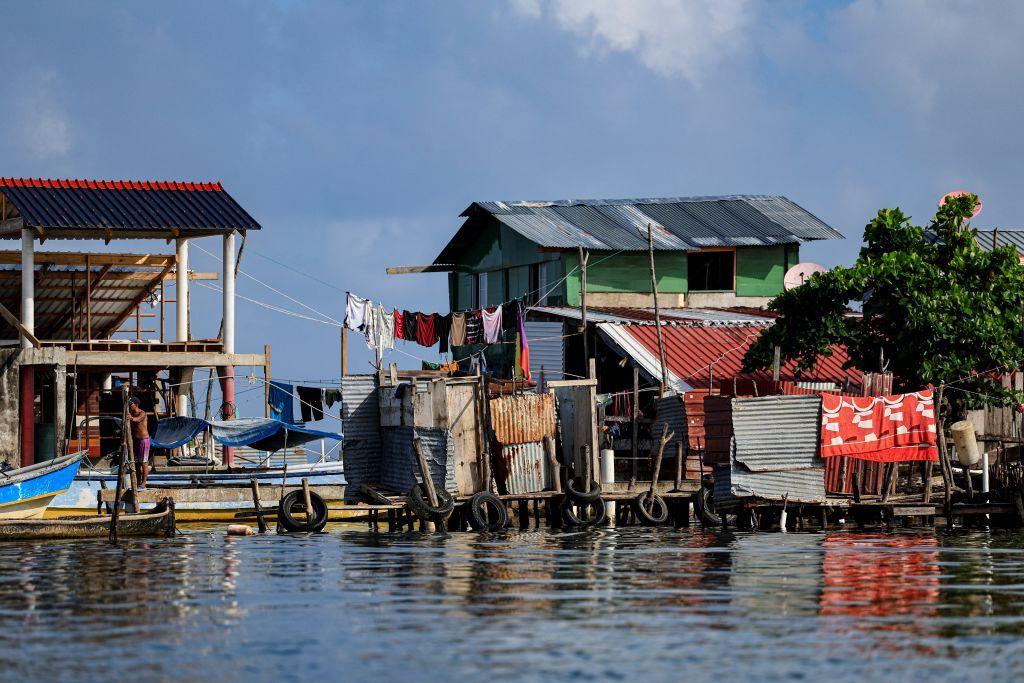 Houses built from wood and corrugated metal on platforms above water, with washing drying, on Gardi Sugdub, June 2024