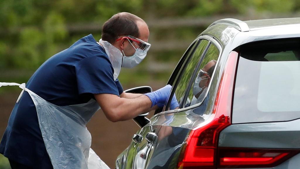 A medical worker takes a coronavirus swab and a drive-in testing centre